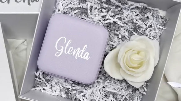 Coffret cadeau avec étui en simili cuir violet personnalisé “Glenda” effet métallisé (feuille métallisée au laser), à côté d’une rose blanche.