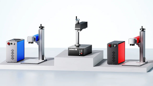 Comparatif de marqueurs laser à fibre OMTech (Q-switched et MOPA) avec têtes galvo sur supports, modèles bleu, noir et rouge.